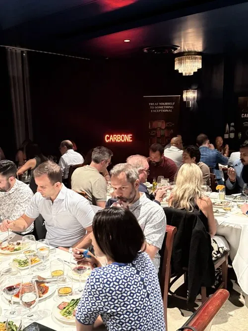 Guests dining under the Carbone neon sign