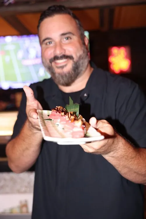 Chef presenting a plate of sashimi at the Seafood Slam