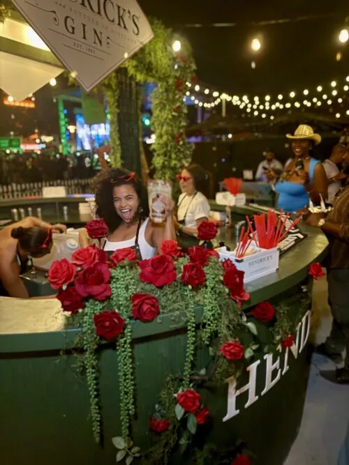 Guest cheering at the rose-covered Hendrick's Gin bar at night