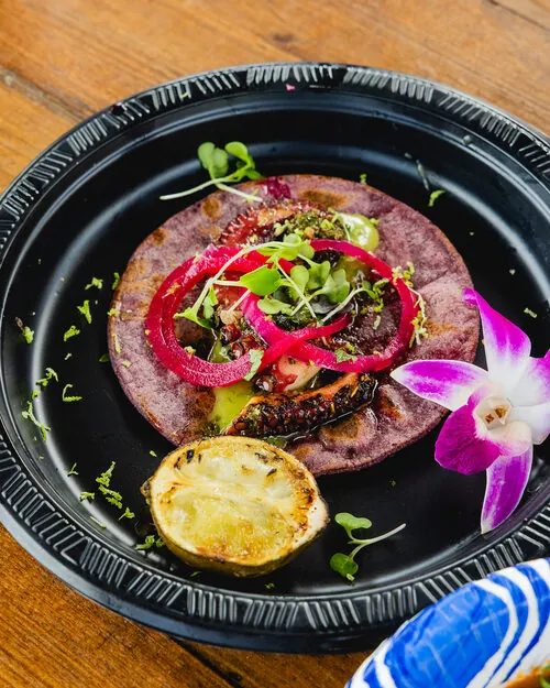 Charred octopus on a blue corn tostada with pickled onion