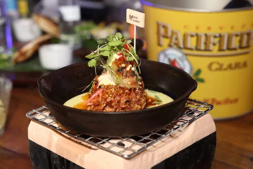 Cast-iron skillet dish served beside a Pacifico bucket