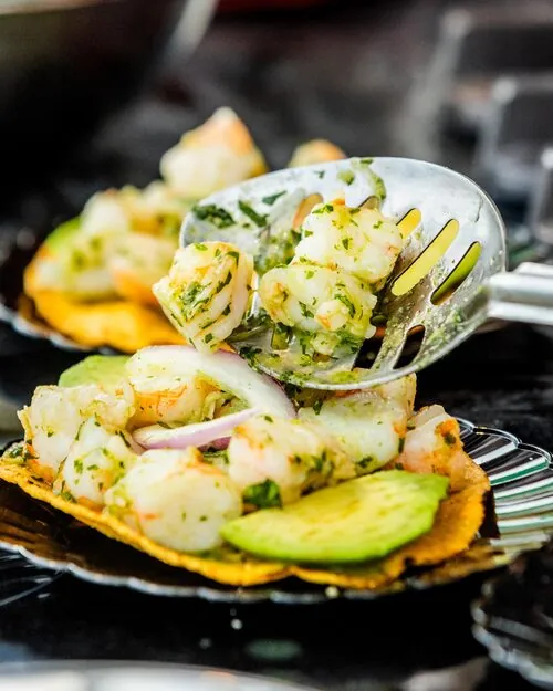 Shrimp ceviche tostadas with avocado being plated